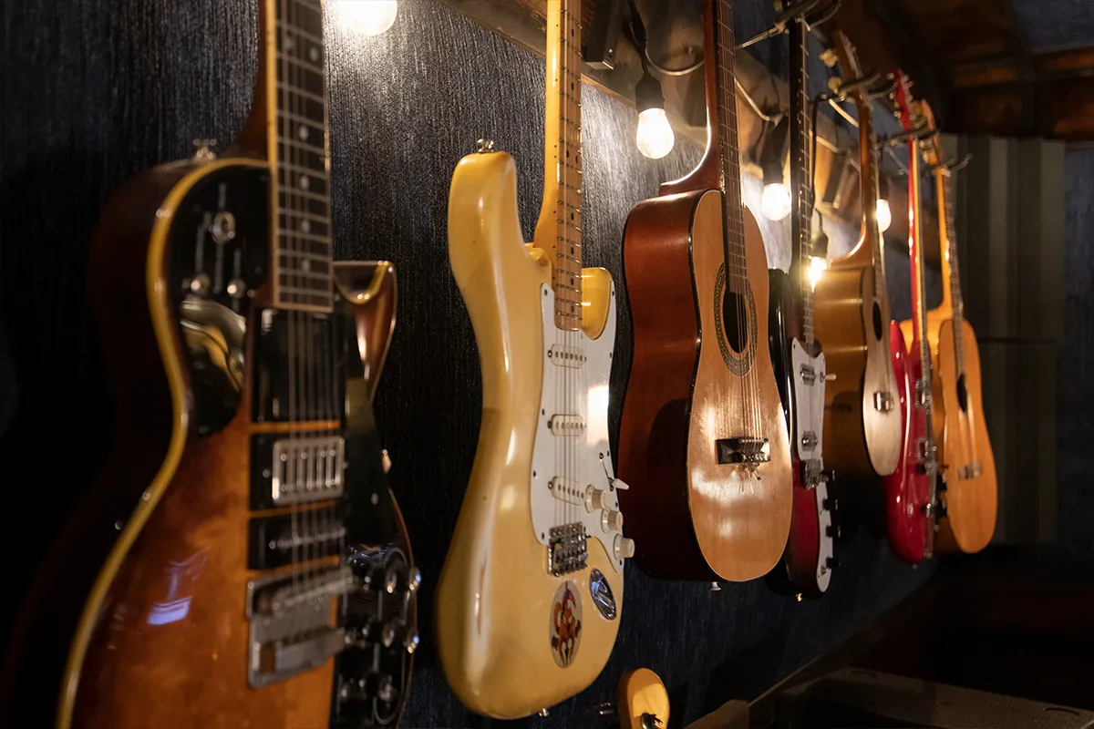 Electric and acoustic guitars hung on a studio wall