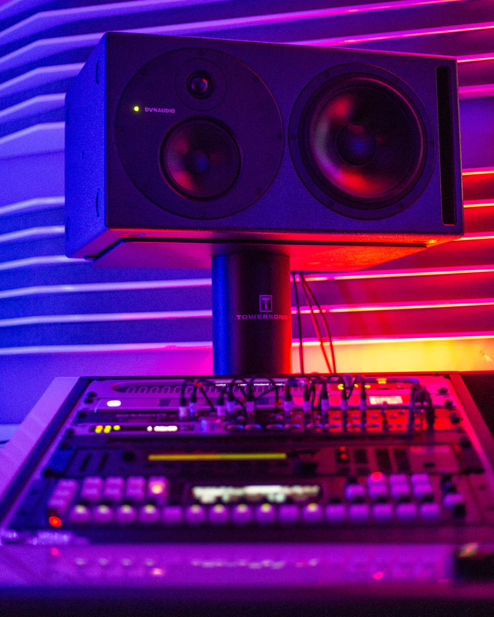 Dynaudio Core 59 studio monitor above an angled rack of studio gear