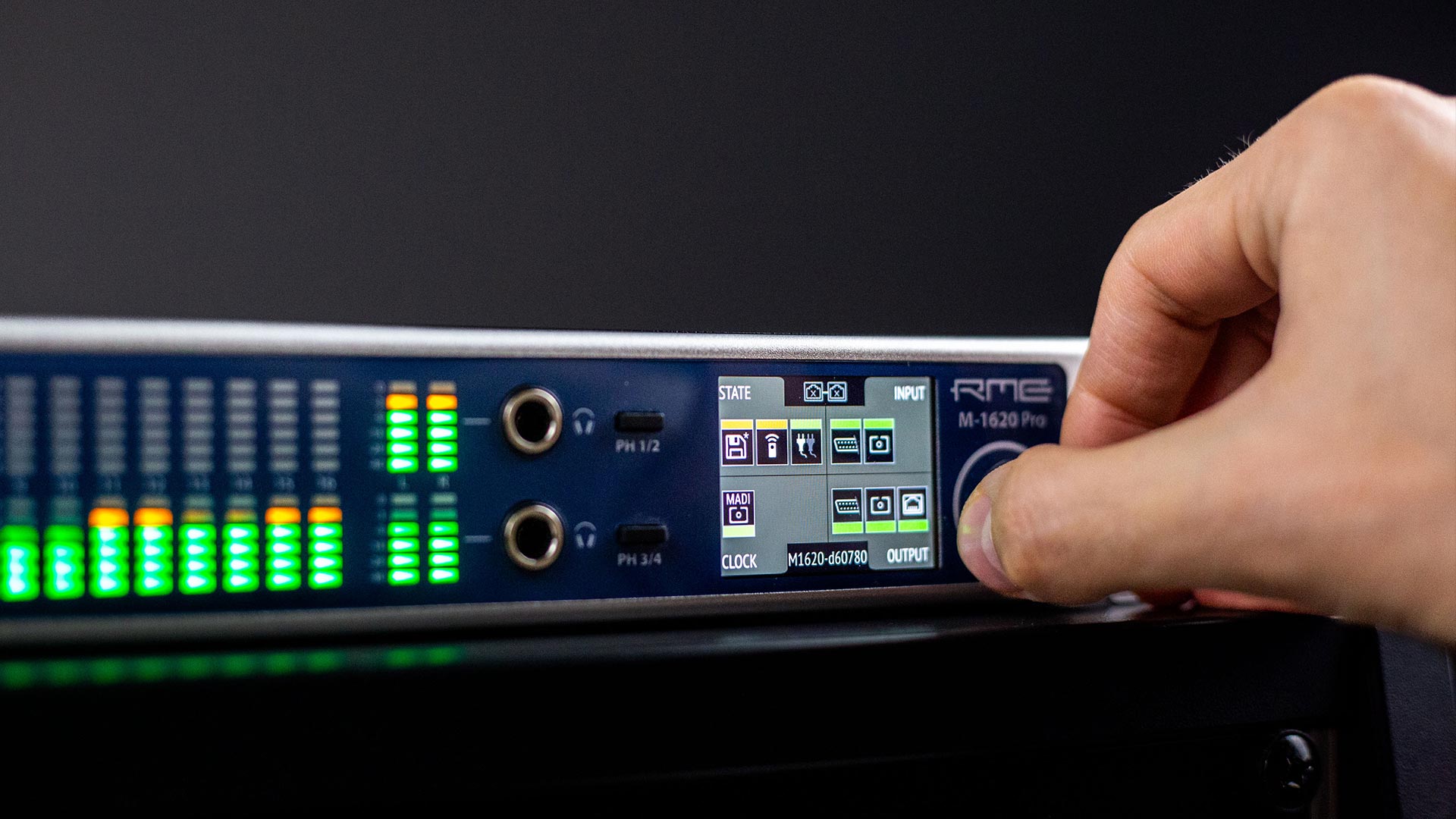 Hand adjusting the front panel of an RME M-1620 Pro