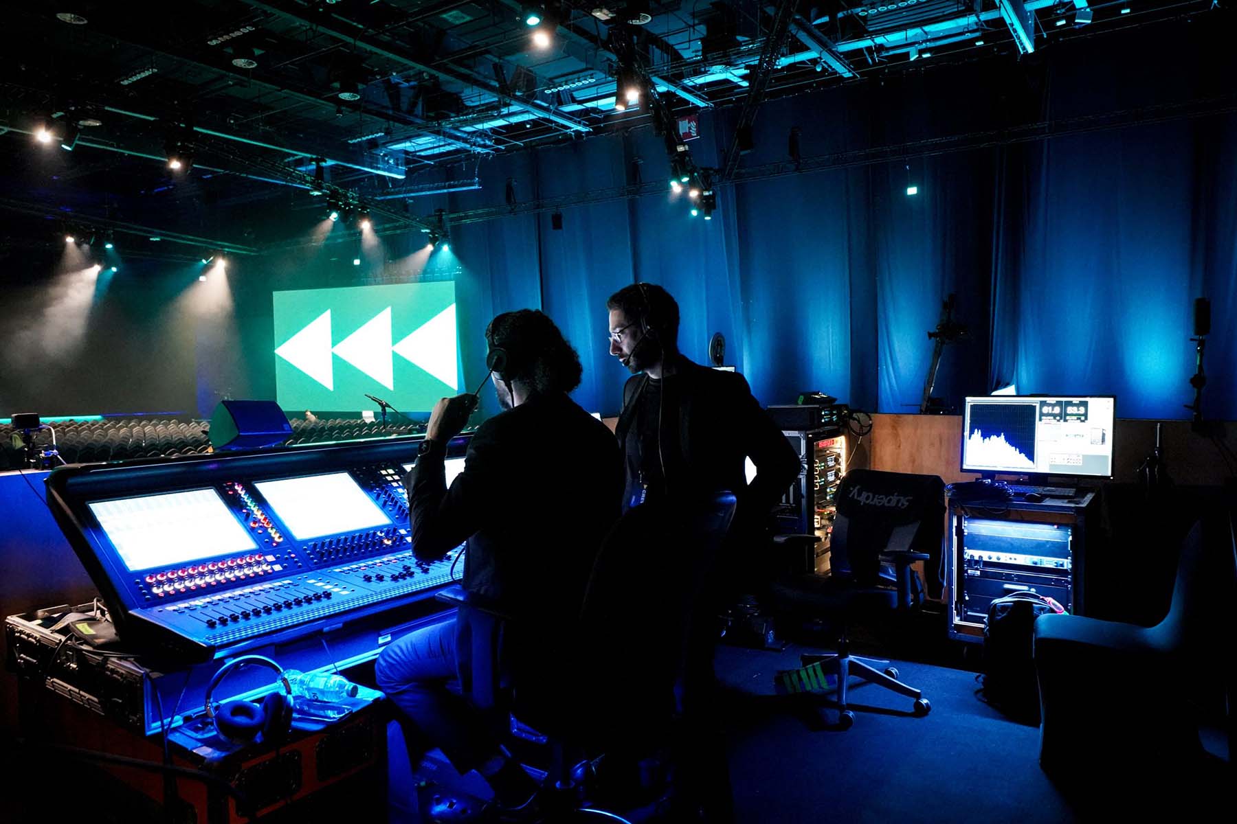 Two crew members at a front of house mixing console