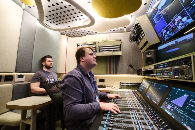 Two men using a Calrec Argo console inside Vivid's Barra OB Truck