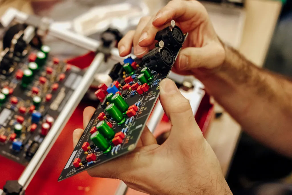 Hands holding a circuit board with two XLR connections